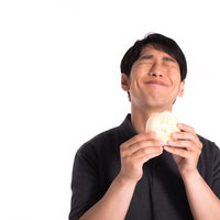 これぞ求めていた味だと551の豚まんを食らう男性の写真