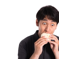 ジューシーな豚まんを食べる男性の表情の写真