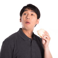 肉まんを片手に落としそうになりながらよそ見する男性の写真