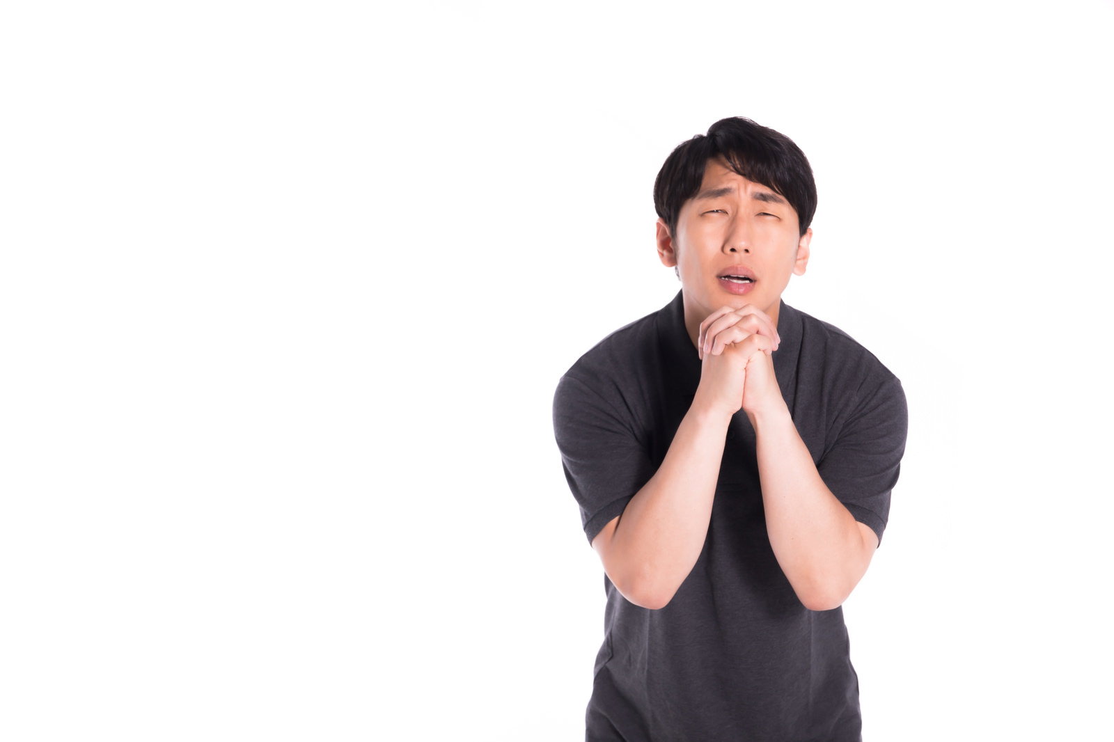 黒いTシャツを着た男性が両手を合わせて祈るポーズをしている［モデル：大川竜弥］