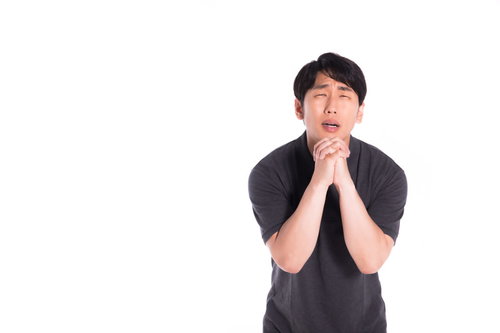 両手を合わせて懺悔する男性、真剣な表情で祈りのポーズ