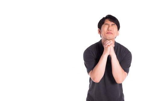 全力で神様に頼み込む男性、両手を合わせて真摯に祈る