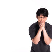 力を込めて祈願する黒いTシャツの男性の写真