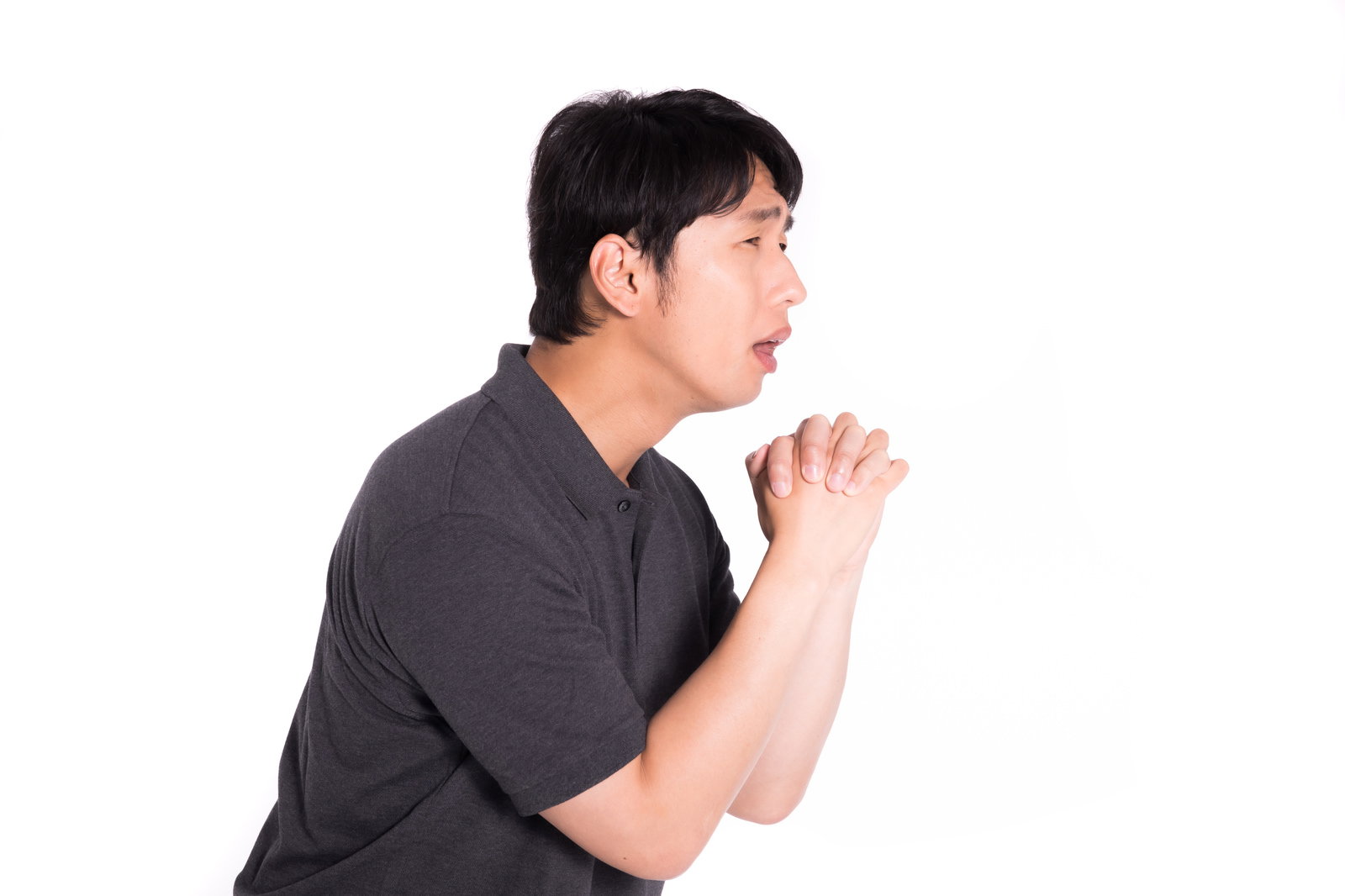 グレーのシャツを着た男性が両手を合わせて祈っている［モデル：大川竜弥］
