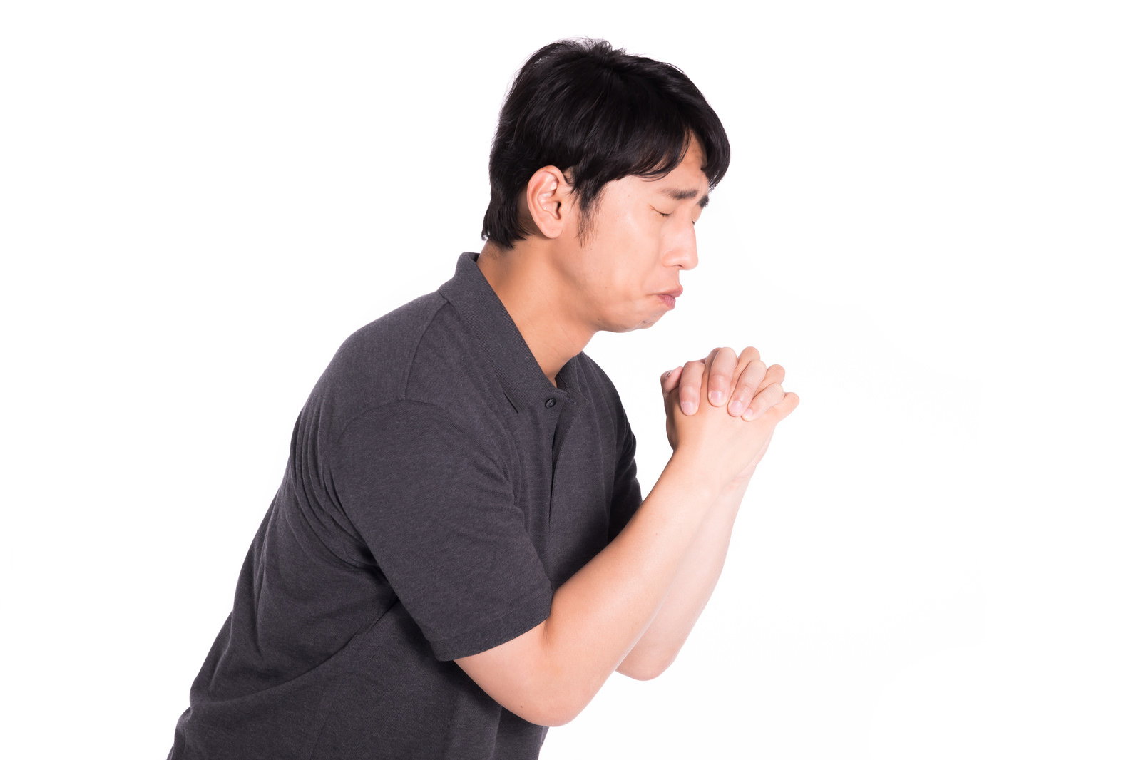 両手を合わせて懺悔し、苦悶の表情を浮かべる男性［モデル：大川竜弥］