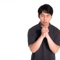 神様に感謝して手を合わせて祈る男性の祈願姿の写真