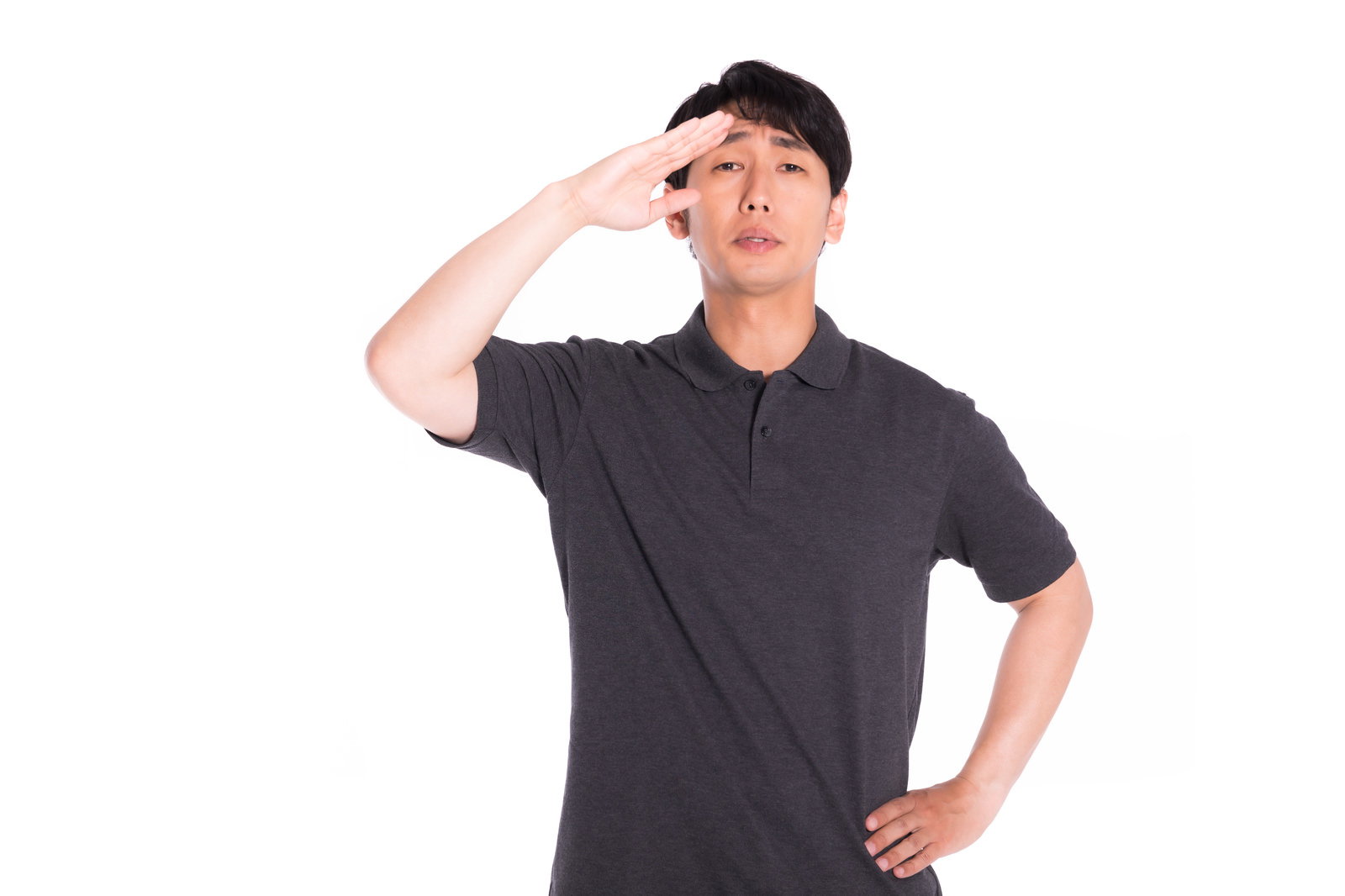 グレーのシャツを着た男性が右手を額に当てて敬礼ポーズを取っている［モデル：大川竜弥］