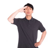 白背景でグレーシャツ姿の敬礼ポーズをする男性の写真