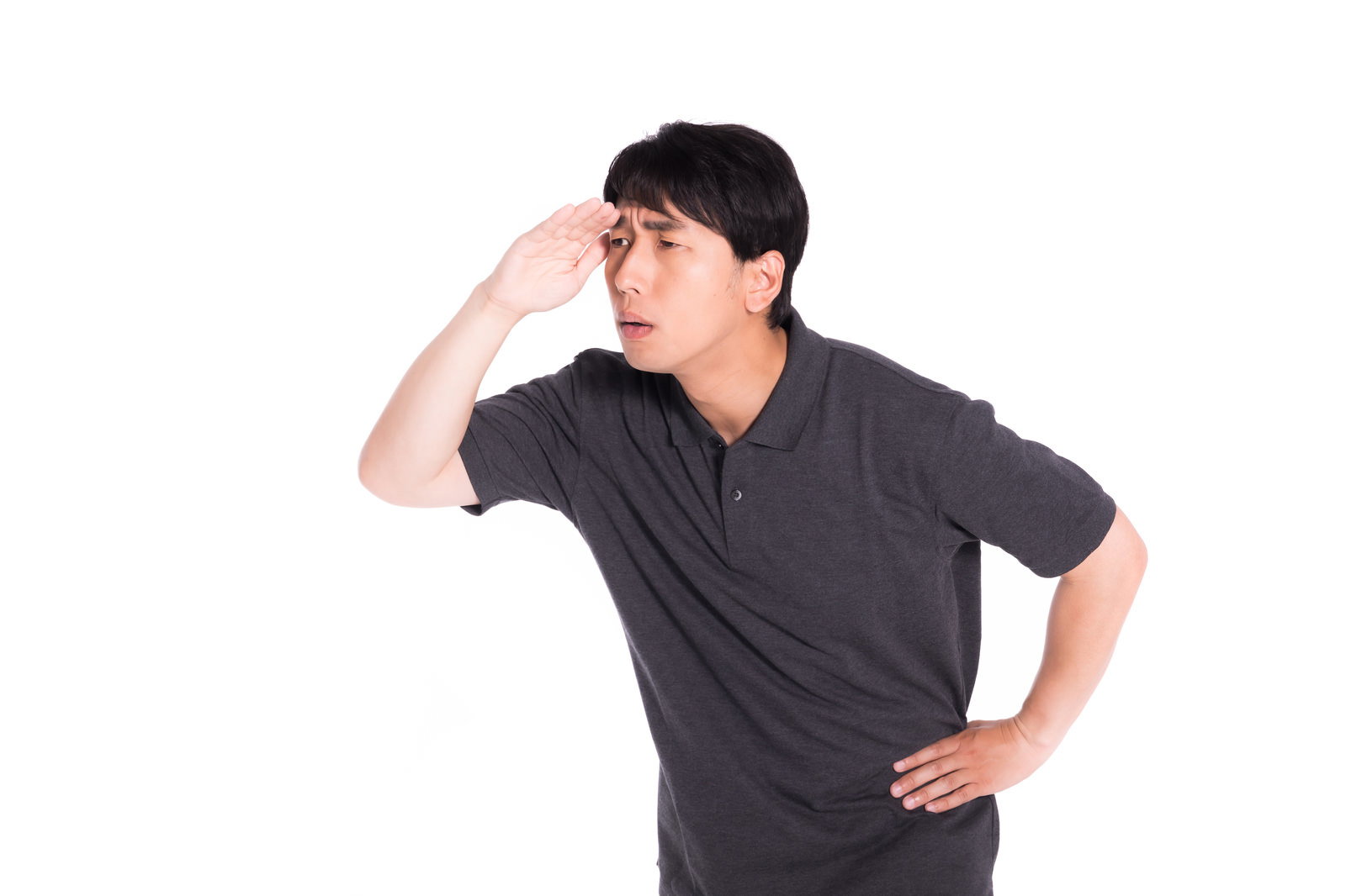 手をかざして目を凝らし、遠くを見つめて確認作業をする男性［モデル：大川竜弥］