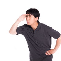 手をかざして目を凝らし遠くを見つめて調査する男性の写真