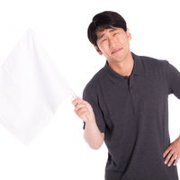 完敗だと白旗をあげる困った表情の男性のリアクションの写真