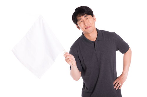 完敗だと白旗をあげる困った表情の男性のリアクション