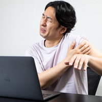 四十肩でタイピングがつらいエンジニア男性の写真