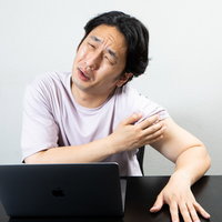 ワクチン接種後の左腕の痛みを訴えるしかめっ面の男性の写真