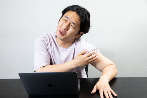 ワクチン接種後の左腕の痛みを訴えるしかめっ面の男性