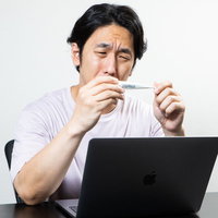 ワクチン接種二日目、副反応で発熱しデスクワークができない男性の写真