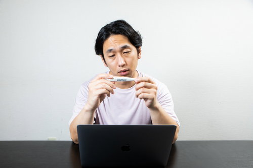 体温計を見て意気消沈するデスクワーク中の男性