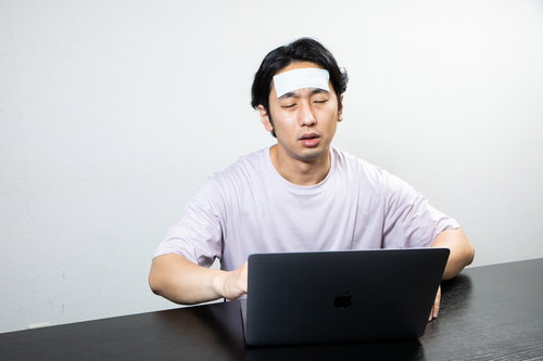 発熱しながらも在宅ワークを続ける男性のデスクワーク