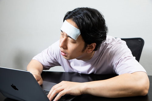具合が悪くてデスクで居眠りする男子社員の疲労