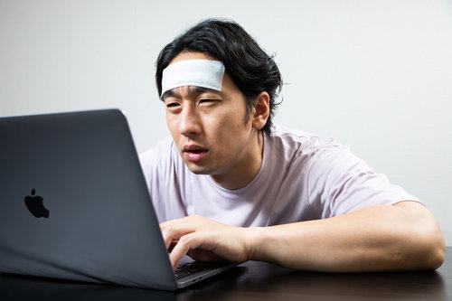 おでこを冷やして最後の力を振り絞る在宅ワーカー男性