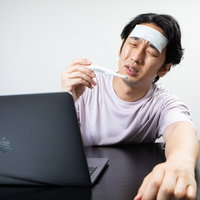 体温計を確認してうなだれる在宅勤務の男性の写真