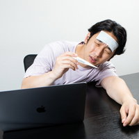 体温計を見て熱のせいだったのかと項垂れる男性の写真