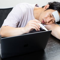 高熱でうなだれるデスクワーク中の在宅ワーカーの写真