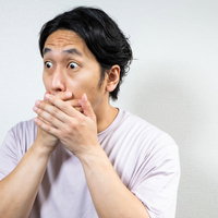 度肝を抜かれて両手で口を覆う男性の驚愕表情の写真