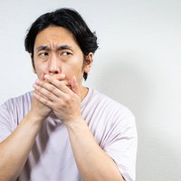 口臭が漏れないように口を覆う男性の驚愕と不安の表情の写真