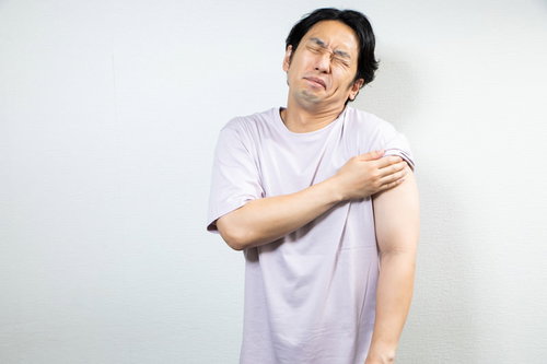 ワクチン接種後に左腕を抑えて困った表情を見せる男性