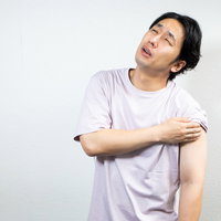 ワクチン注射の鈍い痛みに顔をしかめる男性の写真