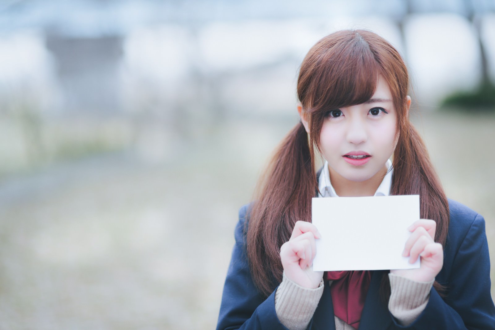 放課後に白紙を掲げる制服姿の女子学生［モデル：河村友歌］