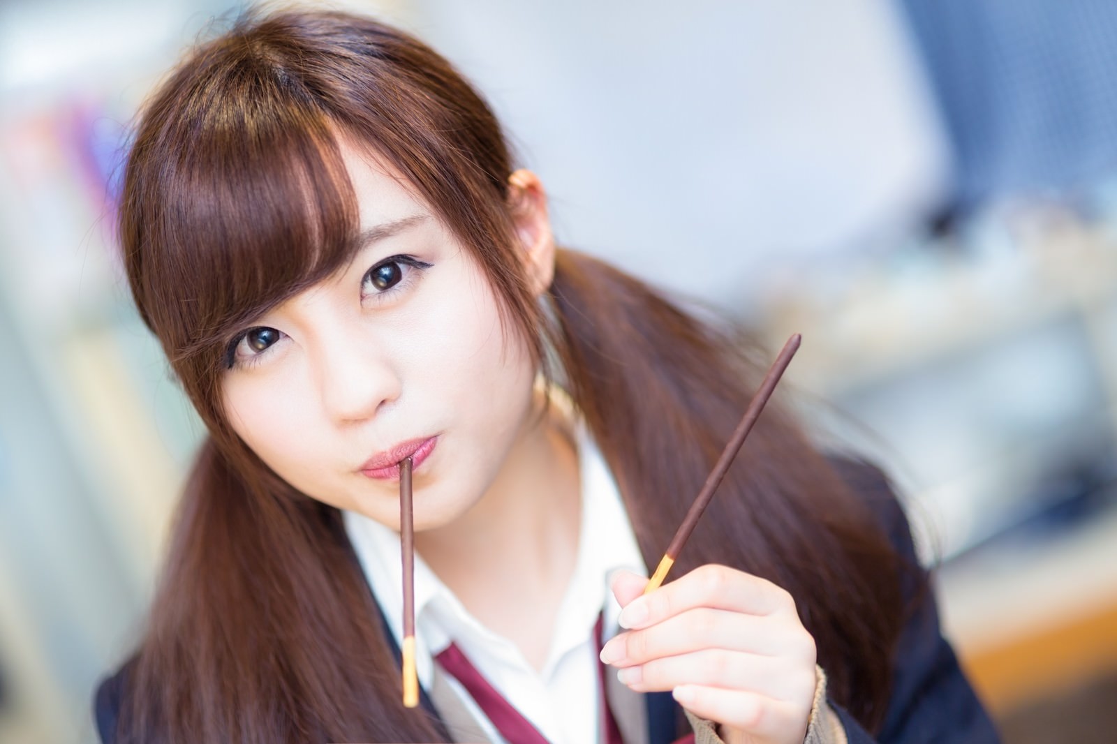 2本の筆を持ち口元に当てる女性［モデル：河村友歌］