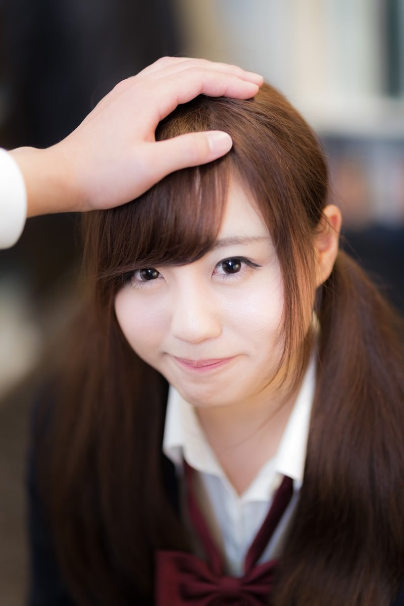 頭に手を添えてニッコリ笑顔を見せる女性［モデル：河村友歌］