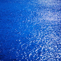 夕日が反射する海の水面、光の粒がキラキラと散らばる光景の写真