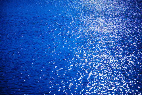 夕日が反射する海の水面、光の粒がキラキラと散らばる光景