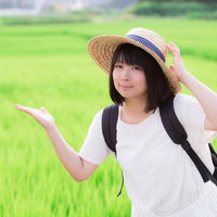 田舎の緑の田んぼと麦わら帽をかぶった女性の夏の風景の写真