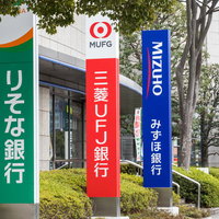 メガバンクの看板が並ぶ金融街の都市風景と経済チャートの写真