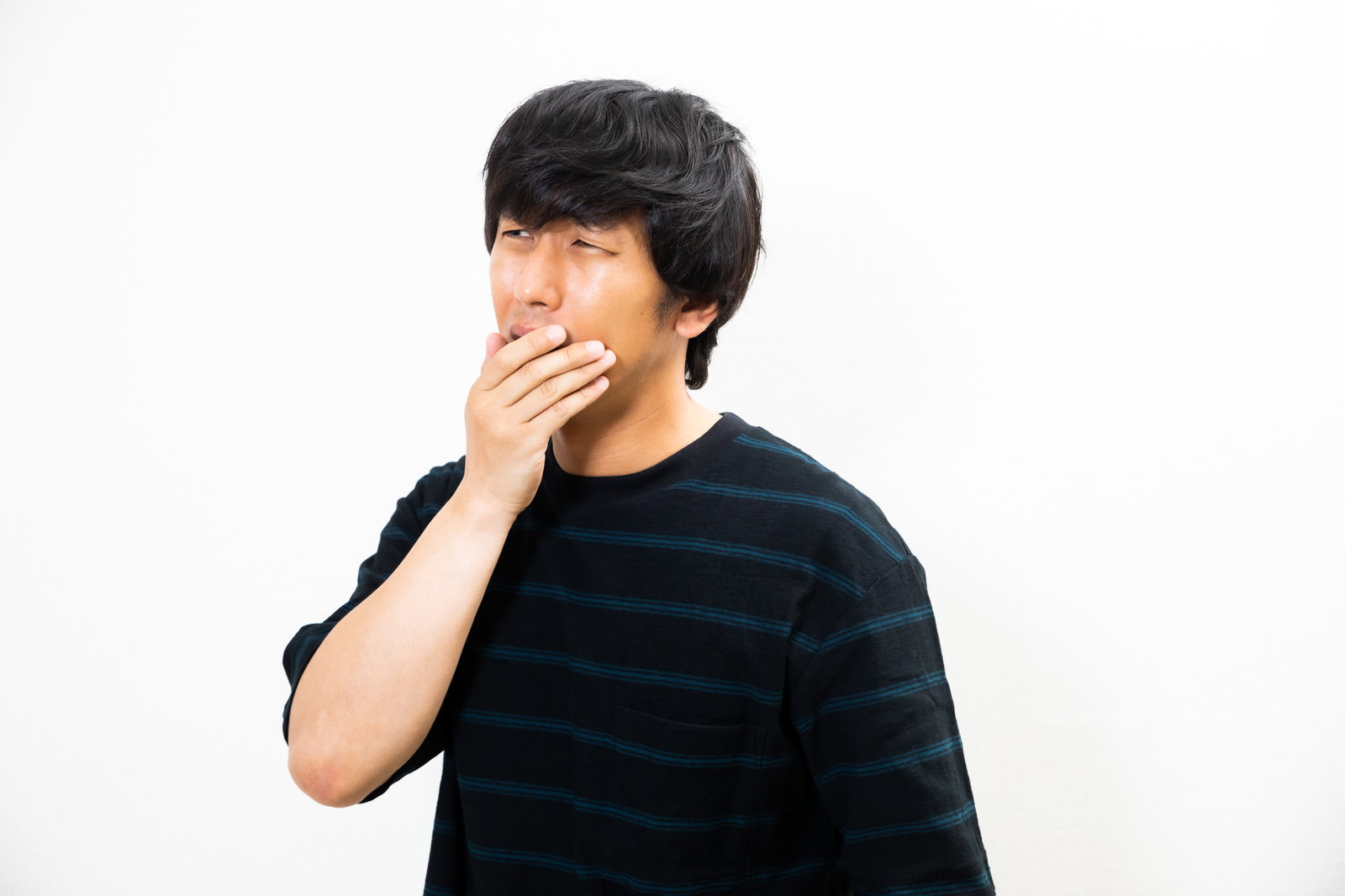 黒いTシャツを着た男性が右手で口を押さえてショックを受けている様子［モデル：大川竜弥］