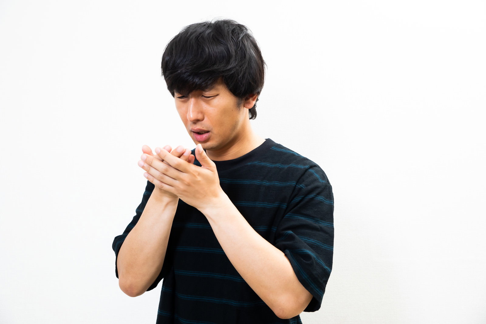 手相を見てショックを受けて青ざめている黒いTシャツの男性［モデル：大川竜弥］