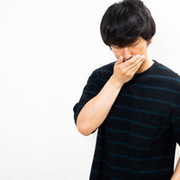 財布落としたかも...と手で口を覆いショックを受ける男性の写真