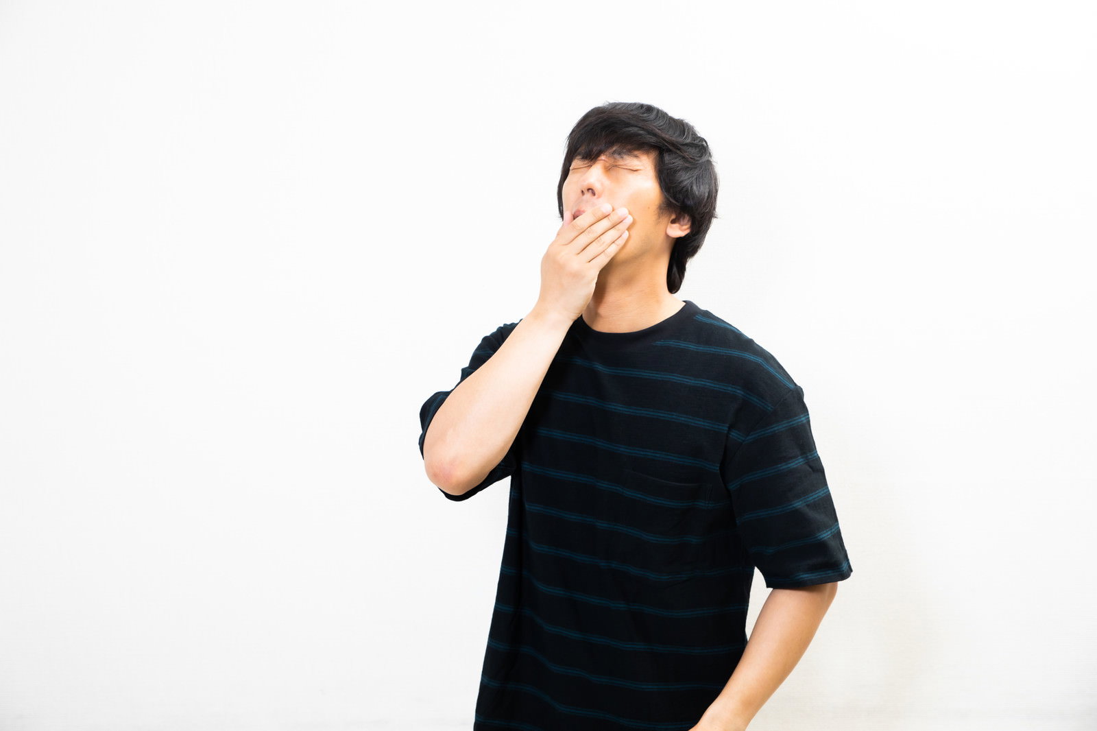 A man in a black t-shirt yawning deeply upon waking up