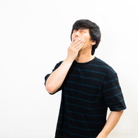 寝起きで大きなあくびをする疲れた男性の朝の目覚めの写真