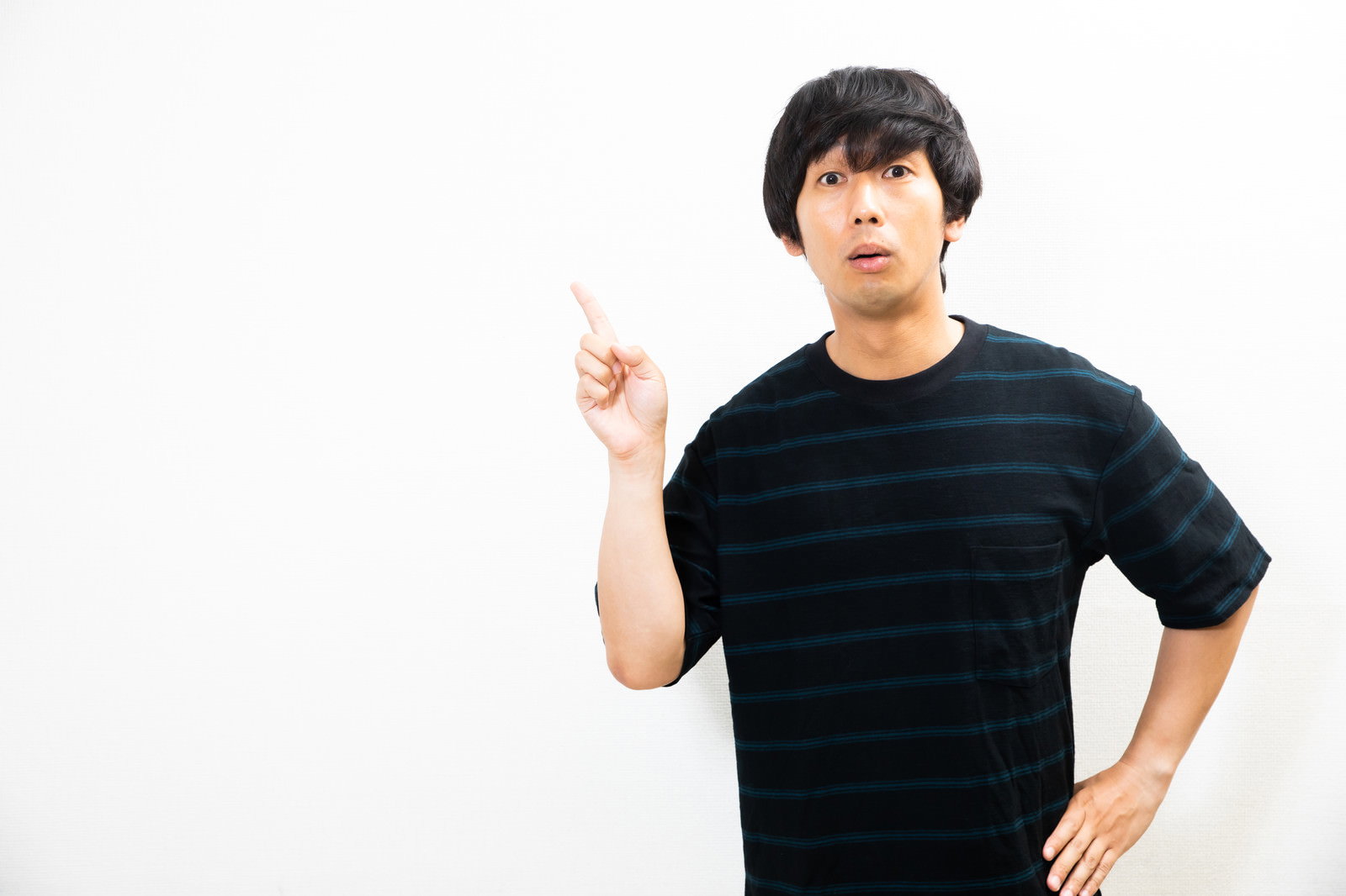 人差し指を上に向ける男性［モデル：大川竜弥］