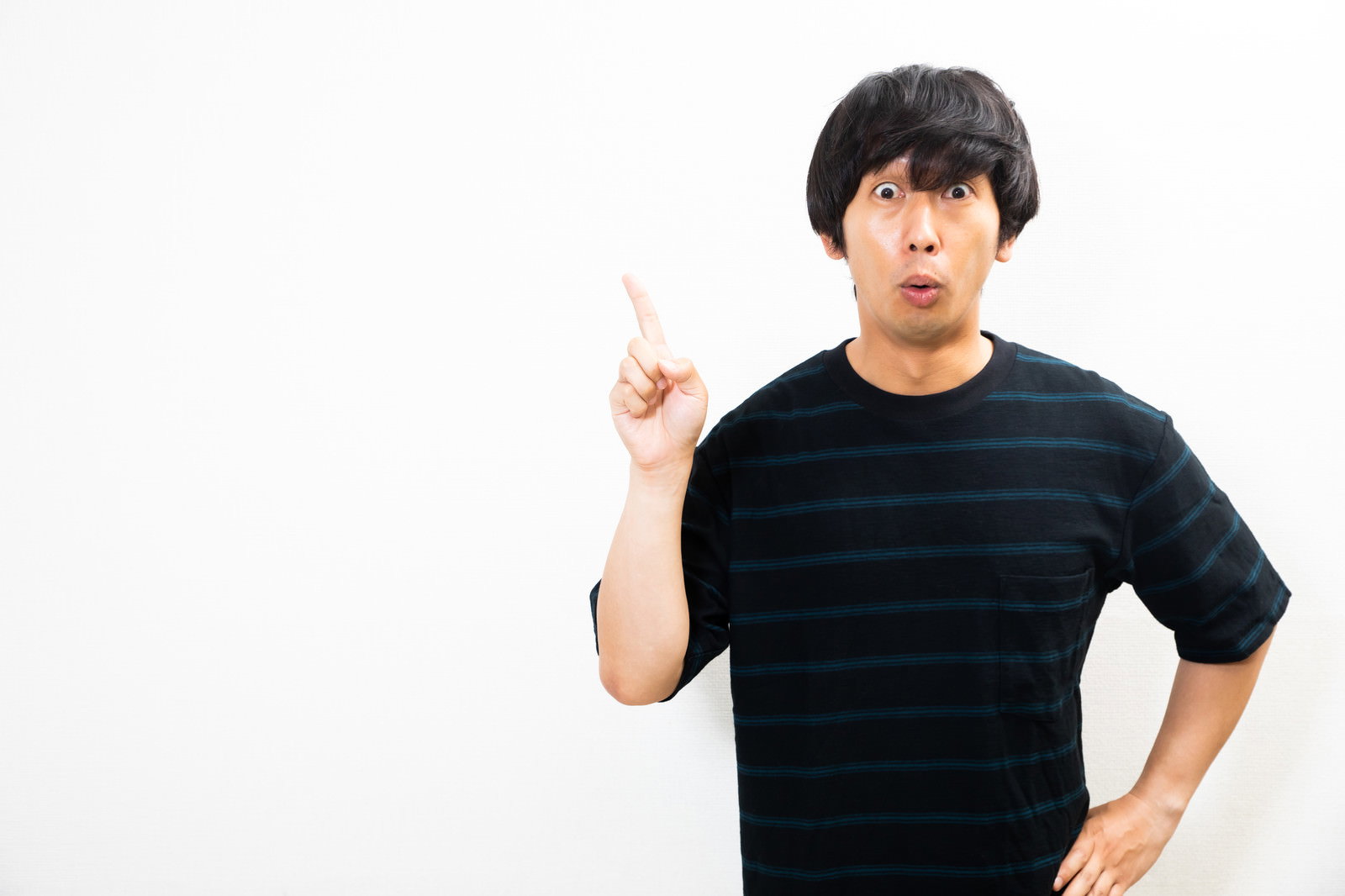 黒いTシャツを着た男性が人差し指を立てて驚いた表情をしている［モデル：大川竜弥］