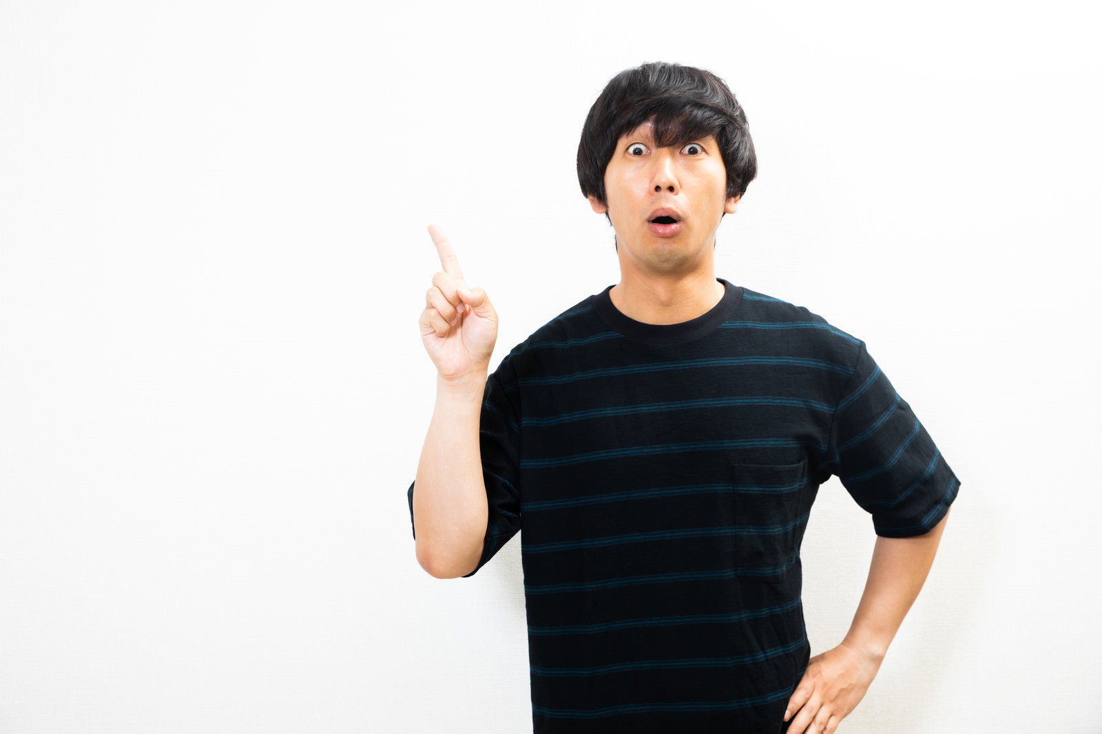 黒いTシャツを着た男性が驚いた表情で人差し指を指している［モデル：大川竜弥］