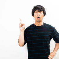 驚き唖然な表情で人差し指をさす黒いTシャツの男性の写真