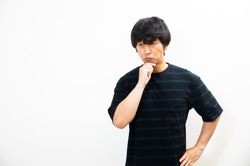 顎に手を当てて考える黒いTシャツを着た男性