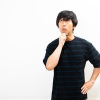 顎に手を当てて上を見つめ不思議がる男性のポートレートの写真