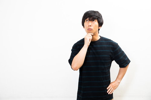 顎に手を当てて上を見つめ不思議がる男性のポートレート